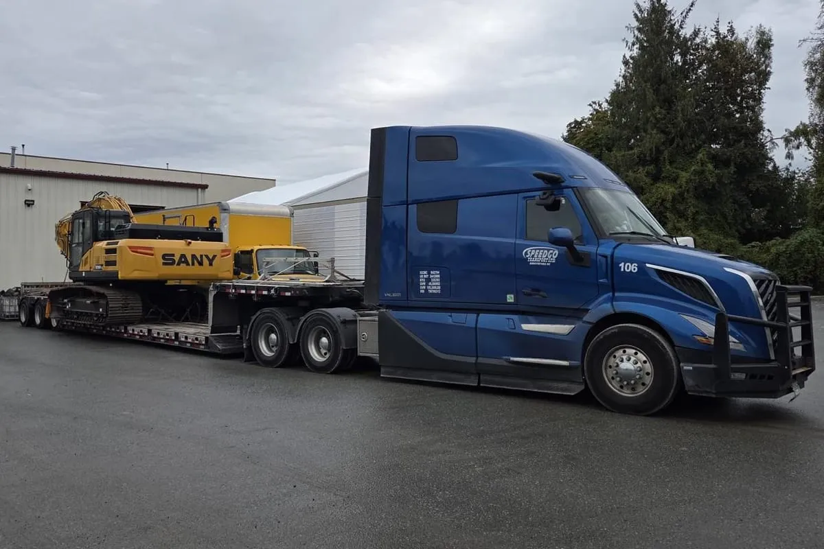 Speedgo Transport truck with a SANY excavator outside a warehouse at the yard